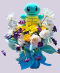 Arreglo floral con peluche de Squirtle rosas blancas lirios amarillos y margaritas moradas en papel turquesa