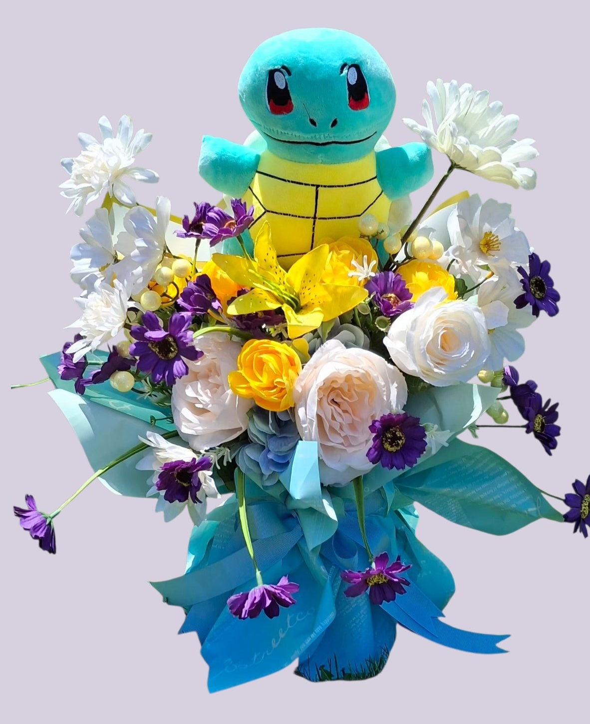 Arreglo floral con peluche de Squirtle rosas blancas lirios amarillos y margaritas moradas en papel turquesa