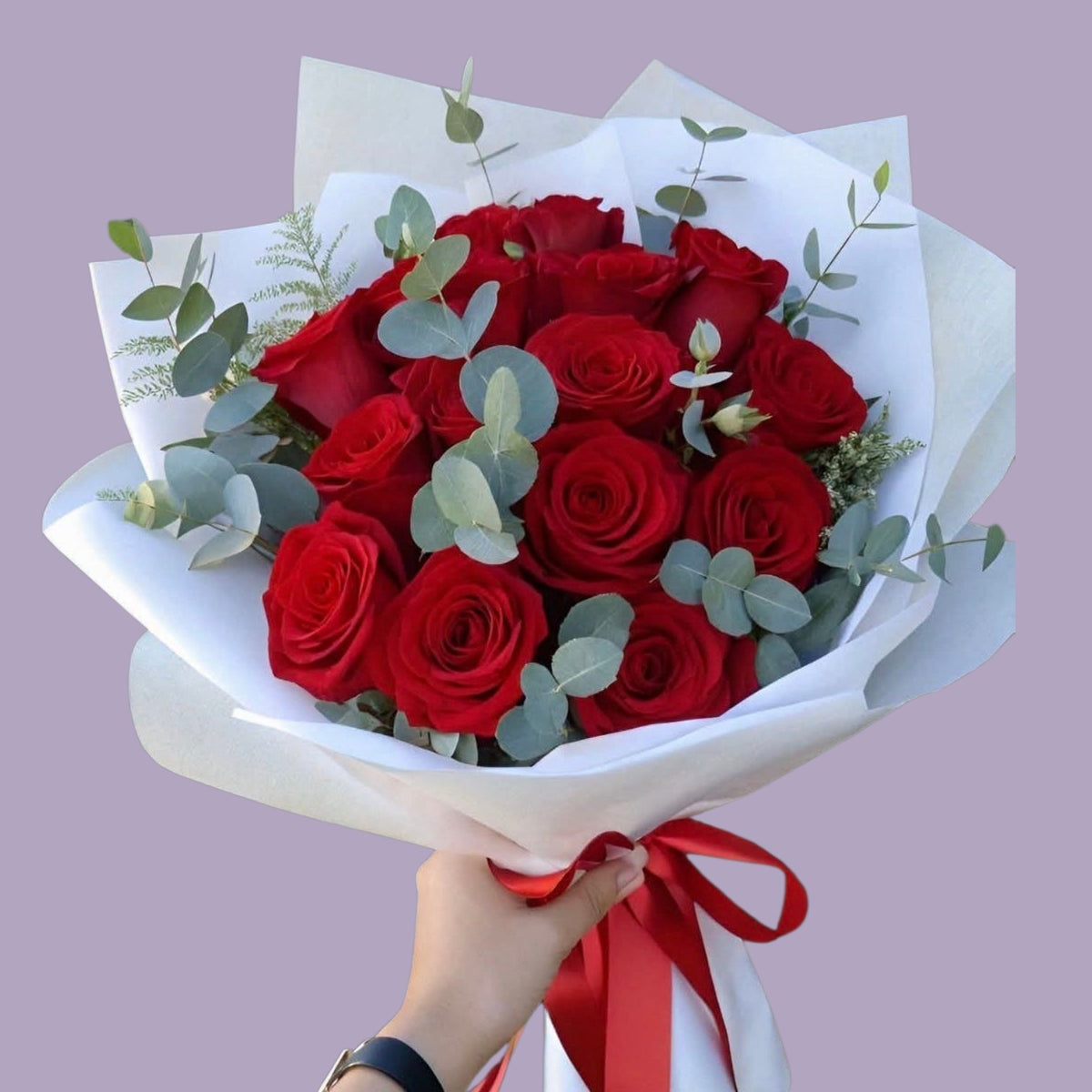 Ramo de rosas rojas con eucalipto envuelto en papel blanco y listón rojo