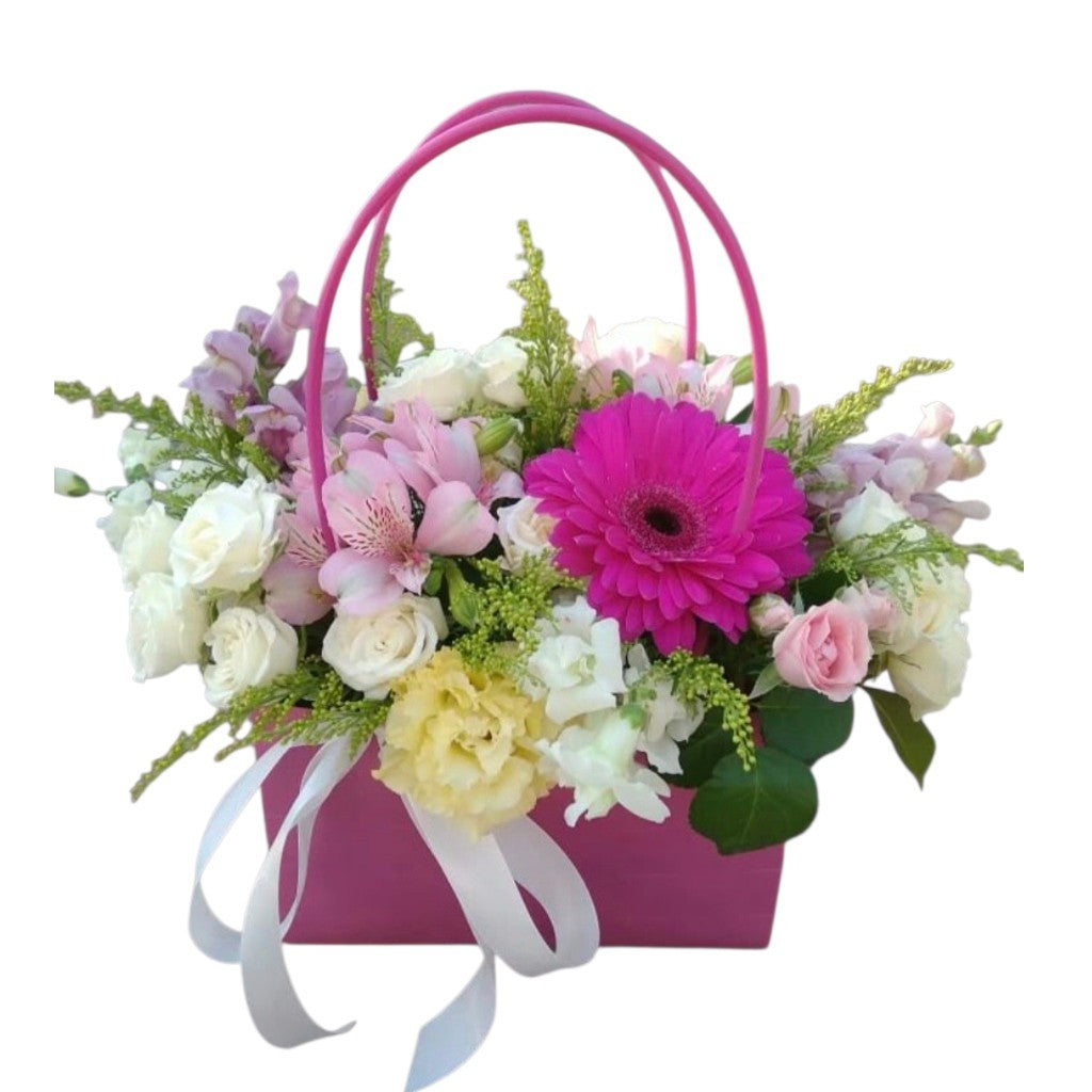 Arreglo de gerbera fucsia, mini rosas y alstroemerias en una caja tipo bolso rosa con lazo blanco