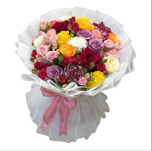 Ramo grande de rosas multicolor y claveles envuelto en papel blanco con moño rosa